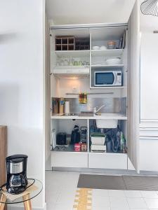 a kitchen with an open pantry with a microwave at Studio Coin Du Bonheur in Saint-François