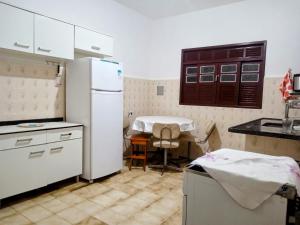 a kitchen with a white refrigerator and a table at Aconchegante casa piuma in Piúma