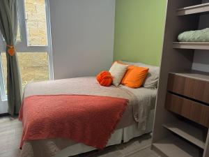 a bedroom with a bed with orange pillows on it at Mirador Santo Tomás - Moderno a minutos de Antigua in Santa Lucía Milpas Altas