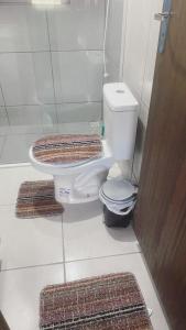 a bathroom with a toilet and two mats on the floor at Pousada Vale das Pedras 03 in Pedras Grandes
