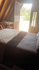 una camera da letto con un letto, un tavolo e una finestra di Pousada Vale das Pedras 03 a Pedras Grandes