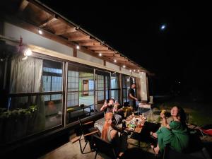 a group of people sitting at a table outside of a house at いすみエンガワのある古民家 in Isumi