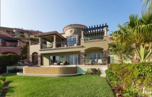 Montecristo Villa at Quivera Los Cabos Vacation Rental في كابو سان لوكاس: منزل كبير أمامه نخلة