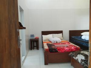 a bedroom with a bed with a teddy bear on it at Harmony Resto & Homestay in Ngadisari