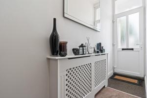 a white hallway with a black vase on a shelf at Cosy 3-bedroom house, garden, fast wi-fi, 6 mins walk to Hull fair, 4 mins drive to MKM stadium perfect for Contractors, Families, HRI hospital locum staff and corporate guests in Hull
