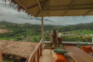 a woman sitting on a balcony looking out at the mountains at สายหมอกบอกรัก น่าน SAIMOK Bokrak NAN in Ban Huai Ti