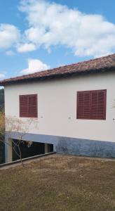 una casa bianca con due finestre sul lato di Casa das Mangueiras no Largo da Matriz de São Gonçalo do Rio das Pedras a Sêrro