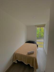 uma cama em um quarto branco com uma janela em Apartamento Urban Manizales em Manizales mais 5 fotografias