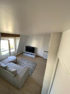 a living room with a white couch and a tv at Calme & RER A proche Paris in Boissy-Saint-Léger