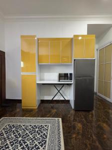 a kitchen with yellow and white cabinets and a refrigerator at Rifqi Ashraf Homestay Kota Bharu in Kota Bharu