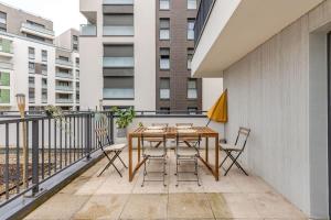 a patio with a wooden table and chairs on a balcony at Luxury apartment near Paris in Bois-Colombes