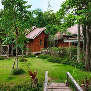 a wooden house with a yard with a staircase at Teak@Teak in Ban Cha-om