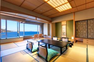 热海热海后乐园酒店(Atami Korakuen Hotel)的一间有桌子、椅子和大海的餐厅 更多19张照片