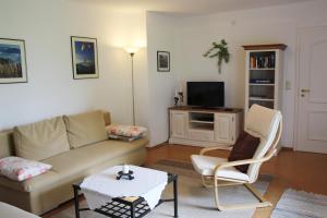 a living room with a couch and chairs and a tv at Landhaus Heinrich in Ruhpolding