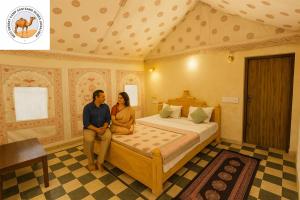 斋沙默尔Best Desert camp sam sand dunes Jaisalmer的坐在房间里床边的男人和女人