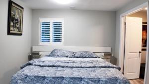 a bedroom with a bed with a blue comforter and a window at 2 Bedroom Walkout Basement Ajax in Ajax