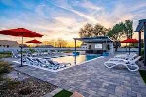a pool with white lounge chairs and an umbrella at The Epic Resort an Acre of Fun for Everyone in Chandler