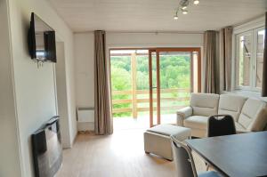 Una sala de estar con un sofá, una mesa y un televisor. en Chalet d'Aventures, en Durbuy