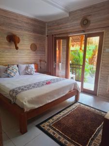 a bedroom with a large bed and a sliding glass door at Riccio Guest House & Cafe in Nusa Lembongan