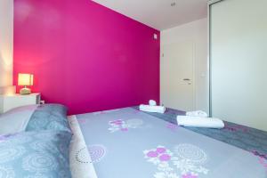 Un dormitorio con una pared rosa y una cama en Apartment KiM, en Dubrovnik