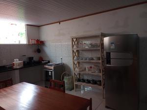 a kitchen with a stainless steel refrigerator and a table at Casa pé do serrão in Ilha de Boipeba