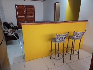 a yellow bar with two stools in a room at Casa pé do serrão in Ilha de Boipeba