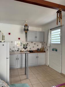 a kitchen with white cabinets and a white refrigerator at Les Ti Kaz a Papé in Deshaies