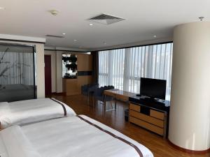 a bedroom with two beds and a desk with a television at Gya Hotel Tangshan Qian'an Fortune Center in Qian'an