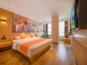 City Comfort Inn Zhanjiang Central People's Hospital High-speed Railway Station في Tchia-k'am: غرفة فندق بسرير كبير مع بطانية برتقال