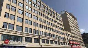 a large building in a city with two tall buildings at Thank Inn Ningxia Yinchuan Helan County Ningxia Jiaotong School in Yinchuan