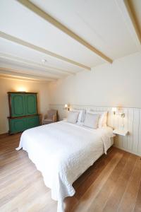 a bedroom with a large white bed with a green door at B&B Maryline in Antwerp