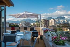 uma varanda com mesas e cadeiras e um guarda-sol em KEIT Hotel em Tirana