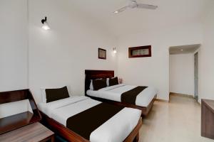 格德拉Super Collection O Vaishno Devi Temple Formerly Hotel The Leaf的一间白墙房间里有两张床