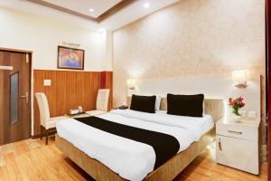 a hotel room with a large bed and a chair at Super Townhouse Brahma Sarovar Formerly Krishna mahal in Kurukshetra