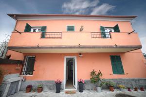 una casa arancione con persiane verdi e piante in vaso di B&B Agorà Sarzana a Sarzana