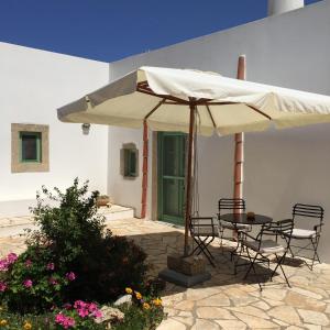 un tavolo e sedie sotto un ombrellone su un patio di Villa Lemonia - Guest House ad Aroniadhiánika