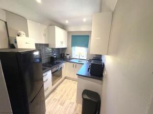 a kitchen with white cabinets and a black refrigerator at 56 Degrees North in Kirkcaldy