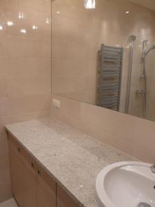 a bathroom with a sink and a shower with a mirror at Apartament Bluesky in Świnoujście