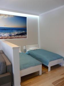 a bedroom with two beds and a painting on the wall at Apartament Bluesky 500m od morza in Świnoujście