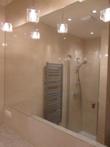 a bathroom with a shower with a mirror and lights at Apartament Bluesky 500m od morza in Świnoujście