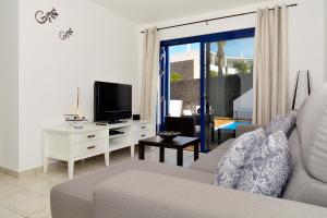 sala de estar con sofá y TV en Lanza Coloradas 20 - PISCINE CHAUFFEE, en Playa Blanca