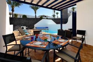 un tavolo da pranzo e sedie su un patio di Lanza Coloradas 20, heated pool a Playa Blanca