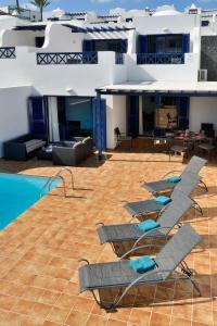 una fila di sedie a sdraio accanto alla piscina di Lanza Coloradas 20 - PISCINE CHAUFFEE a Playa Blanca