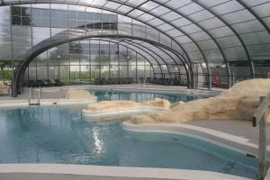 a swimming pool in a building with rocks in the water at Camping des Roses in Quend