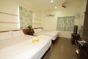 a hotel room with two beds and a tv at Xiang Yang Lan Tian Homestay in Taitung City