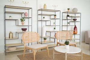 two chairs and a table in front of shelves with plants at Hotel Ankaa - Adults Only in Porto Cristo
