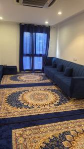 a living room with a blue couch and a rug at Vbx in Muscat