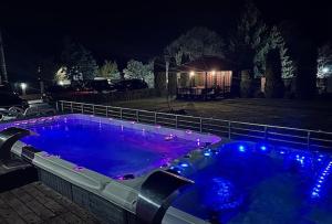 a large swimming pool with blue lights in a yard at night at Луксозна вила - Стрелча, джакузи с минерална вода in Strelcha