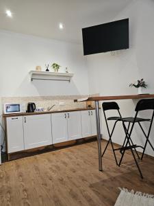 a kitchen with white cabinets and a desk with a television on the wall at Apatments Prague by Yuliia in Prague