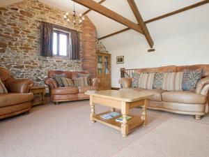 a living room with leather couches and a table at Swallows Cottage in Bideford